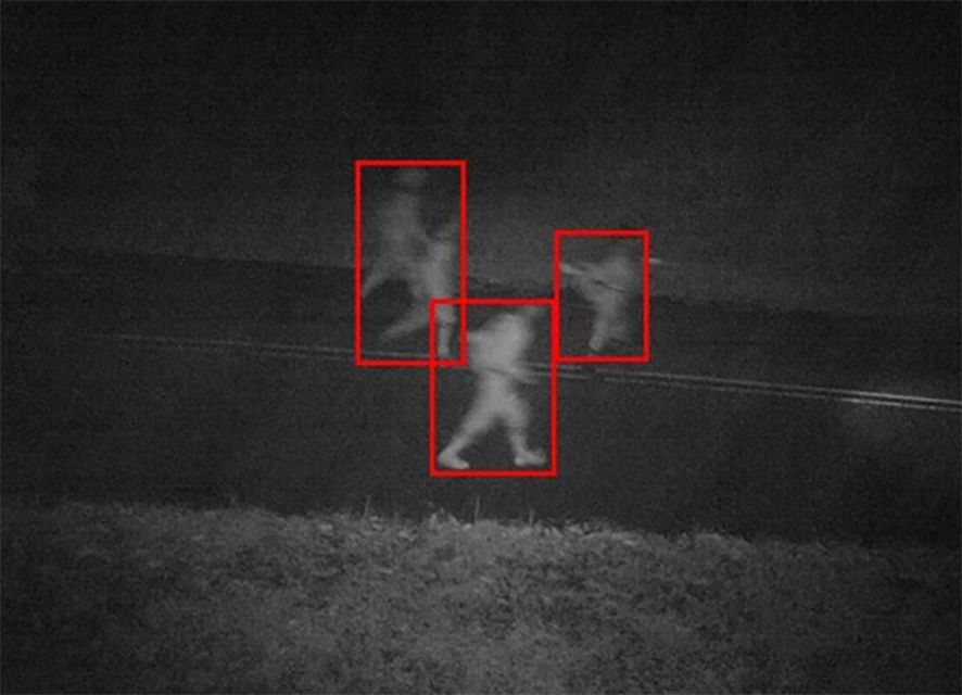 Security camera image showing poachers detected on a paved road at night, each highlighted by a red detection box. The poachers were eventually apprehended due to alerts from wpsWatch. Credit Wildlife Protection Solutions.