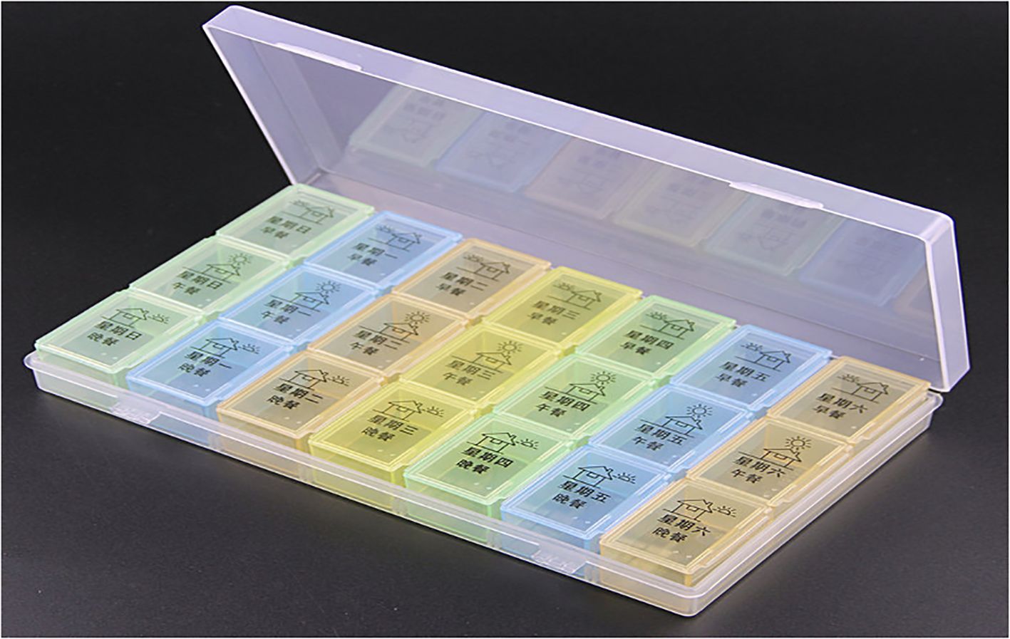 A pill organizer with multiple compartments, each labeled in Chinese characters, indicating different days of the week. The compartments are in various pastel colors including green, yellow, and blue, and are enclosed in a transparent plastic case with the lid open.