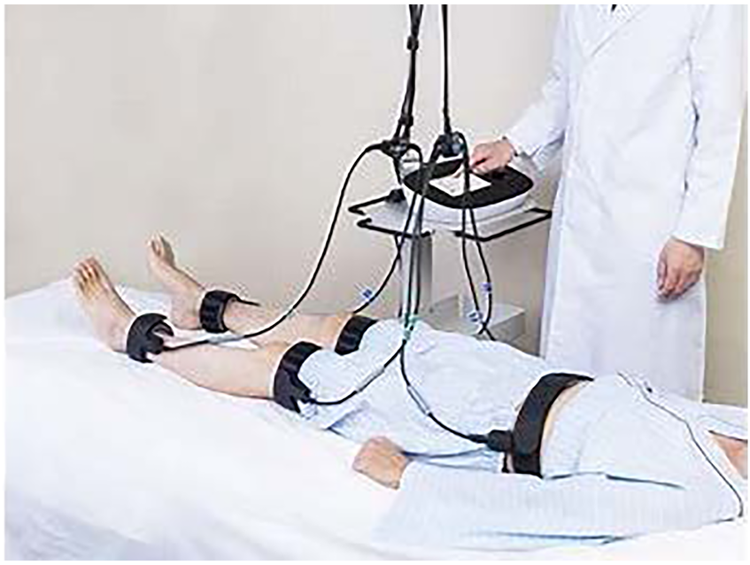 A person lies on a medical examination table with straps and sensors attached to their legs and abdomen. A healthcare professional in a lab coat operates a device connected to the sensors.