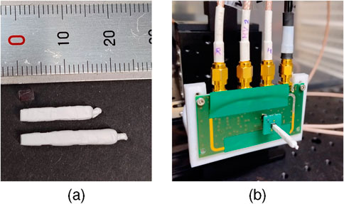 (a) Two white crystals placed beside a ruler, indicating their different size. (b) A green circuit board connected to several cables with gold connectors, an SiPM with a crystal wrapped in white on top is plugged into the board.