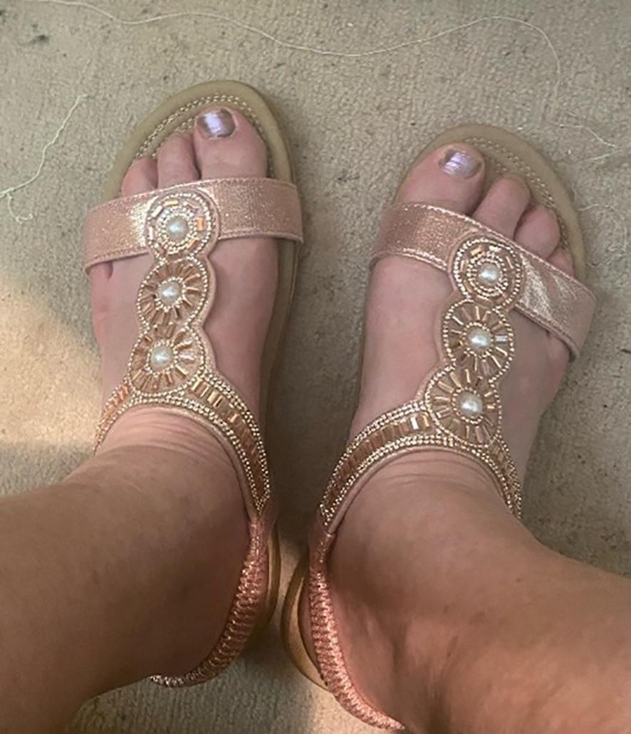 Photograph of two bear feet with the toenails painted silver, wearing gold sparkly sandals.
