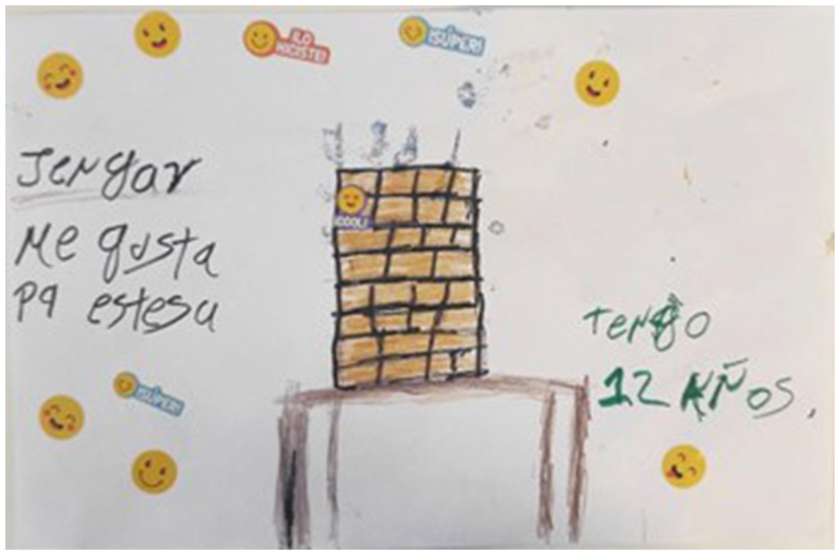 Children's drawing featuring a Jenga tower on a table with handwritten text in Spanish. The text says “Jenga me gusta porque me estresa,” (translation: I like Jenga because it stresses me out). The phrase “tengo 12 años” indicates that the author is 12 years old. The background includes smiley face stickers.