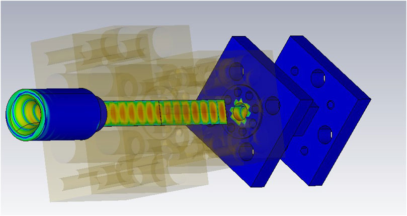 Diagram of a mechanical assembly featuring blue and green components. The design includes a cylindrical section on the left connecting to a rectangular panel on the right, both having multiple circular and star-shaped elements. Translucent sections reveal internal structures.