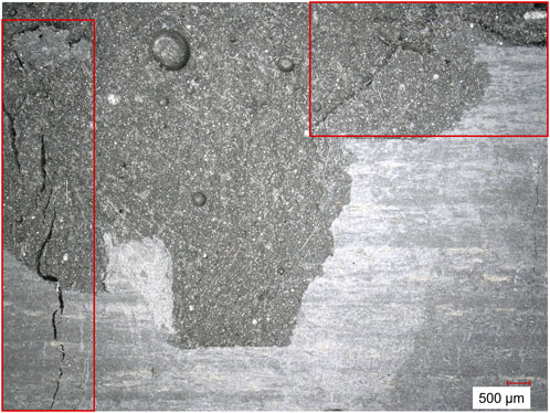 Close-up of a material's surface showing varying textures and cracks. Two red rectangles highlight areas with additional cracking and irregularities. A scale marker indicates a length of five hundred micrometers.