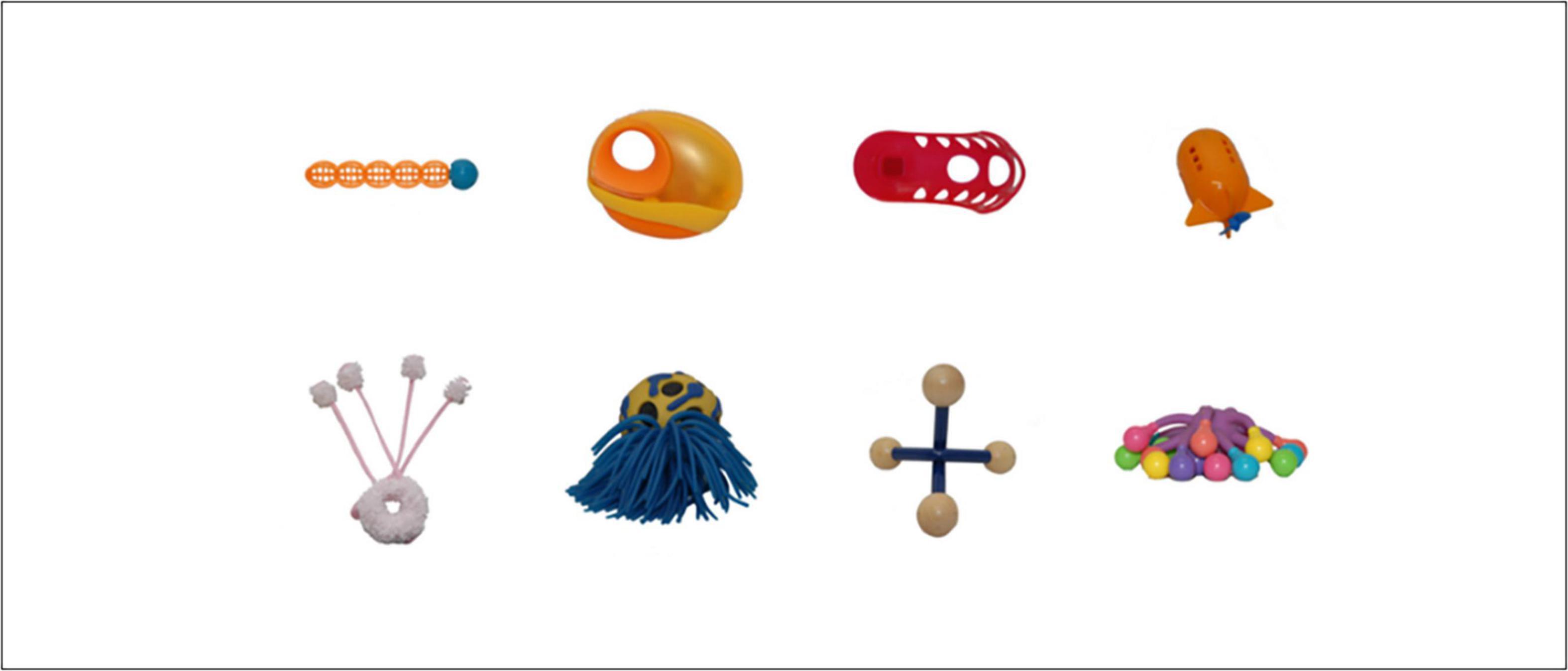 Assorted colorful novel (nonsense) objects arranged in two rows. Top row from left: orange and blue ball with segments, orange object with a hole, red object with holes, orange rocket-shaped object. Bottom row from left: white soft donut with light pink and white soft antennas, blue and yellow ball with tassels, beige and blue four-pronged massager-like object, colorful rubber octopus-like object.