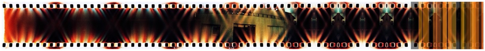 Abstract image of a film strip featuring an overlay of colorful light patterns and geometric shapes. The center displays a blurred architectural structure, with hues of orange, red, and black dominating the design.
