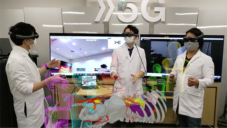 Three healthcare professionals wearing mixed reality headsets engage in a collaborative 3D anatomical simulation within a high-tech environment marked by a prominent