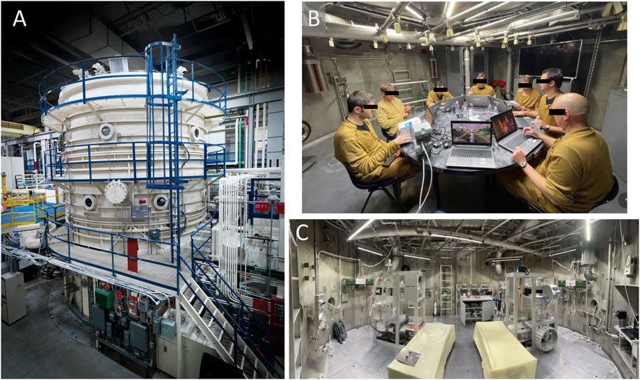 A composite image showing three panels: Panel A displays a large, cylindrical, 3-story metal chamber with blue railings and several access points, situated in an industrial building. Panel B depicts several individuals in brown uniforms sitting around a table with laptops and equipment inside a metallic room, with blackout sensors across their eyes. Panel C shows an industrial room with various machinery and EVA equipment stations, including two covered structures in the foreground and exposed pipes and cables on the walls.