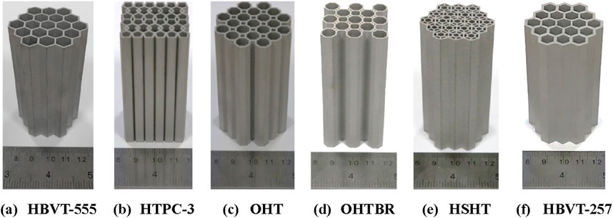 Six hexagonal tube structures labeled (a) HBVT-555, (b) HTPC-3, (c) OHT, (d) OHTBR, (e) HSHT, and (f) HBVT-257 are arranged side by side. Each structure is placed above a ruler for scale reference. The tubes vary in design, but all have a similar honeycomb pattern.