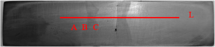 A grayscale image of a metallic surface with a prominent horizontal red line labeled