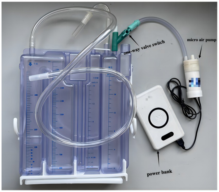 Medical device setup featuring a clear liquid measurement container with blue markings and attached tubing. A one-way valve switch connects to a micro air pump, linked to a power bank via a black cable.