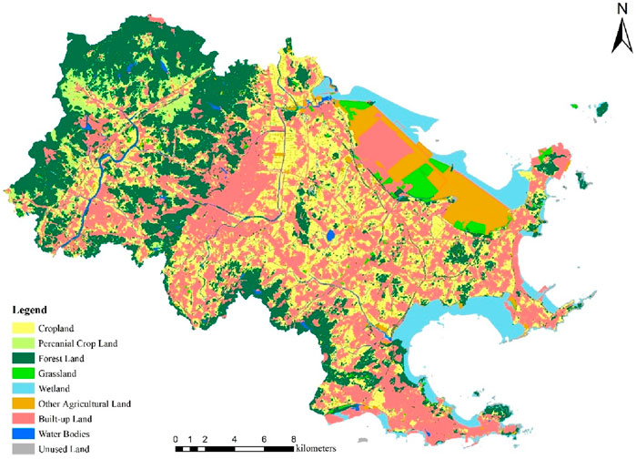 Land use map of a coastal region showing various categories: green for forest land, light green for cropland, light yellow for perennial cropland, pale yellow for grassland, blue for water bodies, pink for built-up land, brown for wetland, orange for other agricultural land, and gray for unused land. The map includes a scale in kilometers and a compass indicating north.