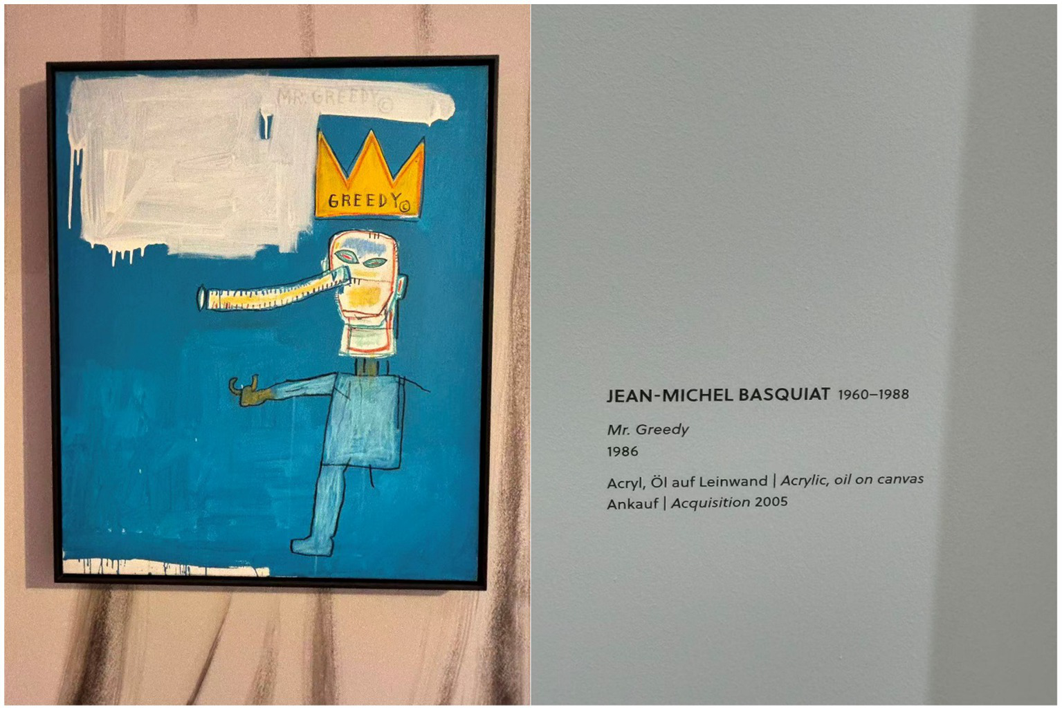 Painting titled “Mr. Greedy” by Jean-Michel Basquiat, dated 1986. Features a figure with a long nose and crown against a blue backdrop. Text on the side details the artwork's acquisition in 2005 and describes it as acrylic and oil on canvas.