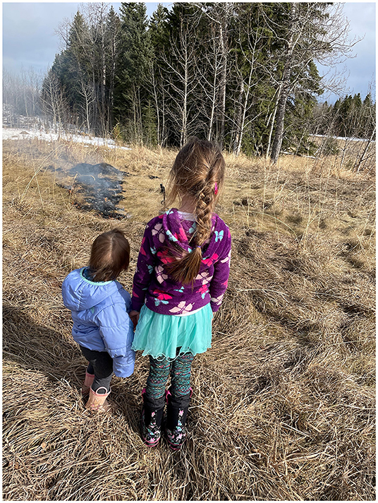 Figure 1 - Indigenous fire practitioner and co-author Amy Cardinal Christianson teaches her daughters how to conduct a safe cultural burn in the early spring.